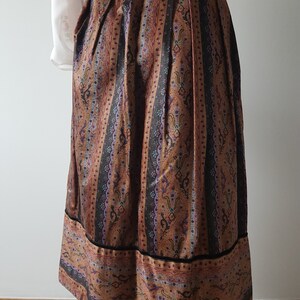 May include: A brown and black patterned skirt with a black waistband. The skirt has a vertical stripe pattern with floral designs.