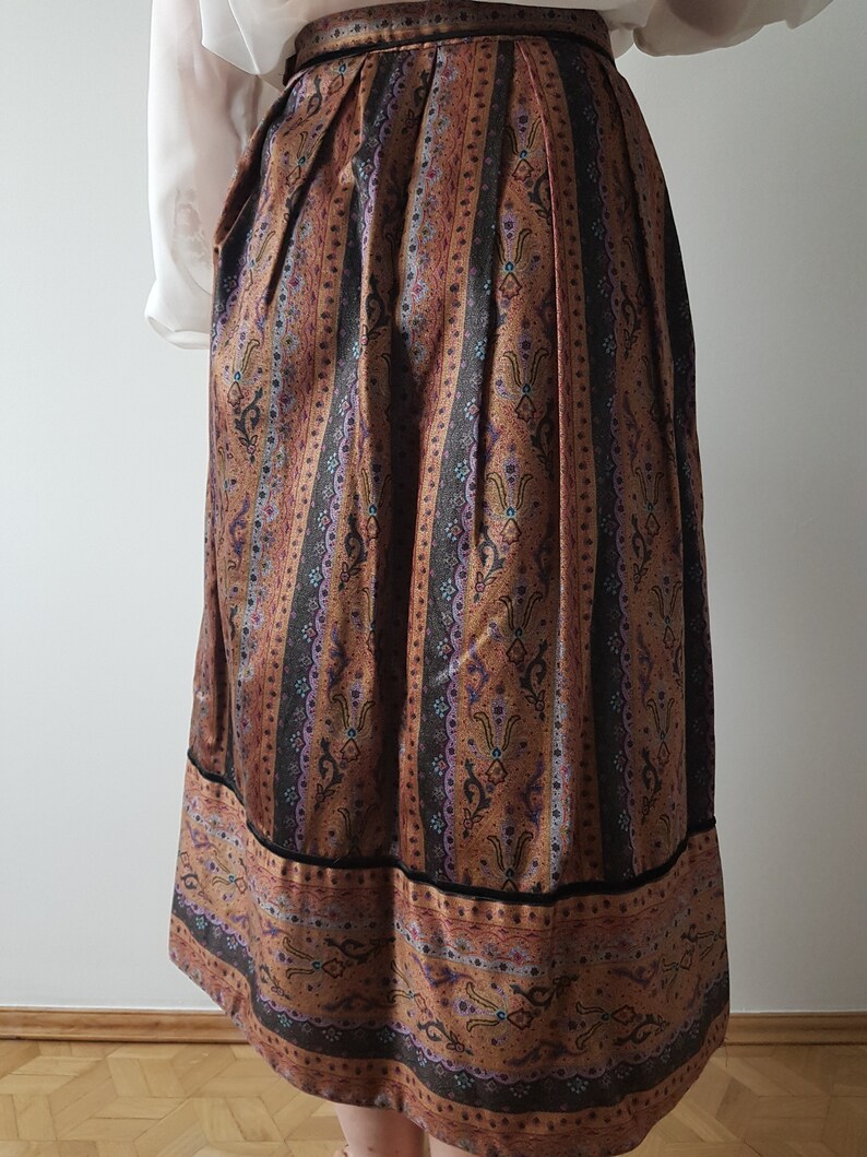 May include: A brown and black patterned skirt with a black waistband. The skirt has a vertical stripe pattern with floral designs.