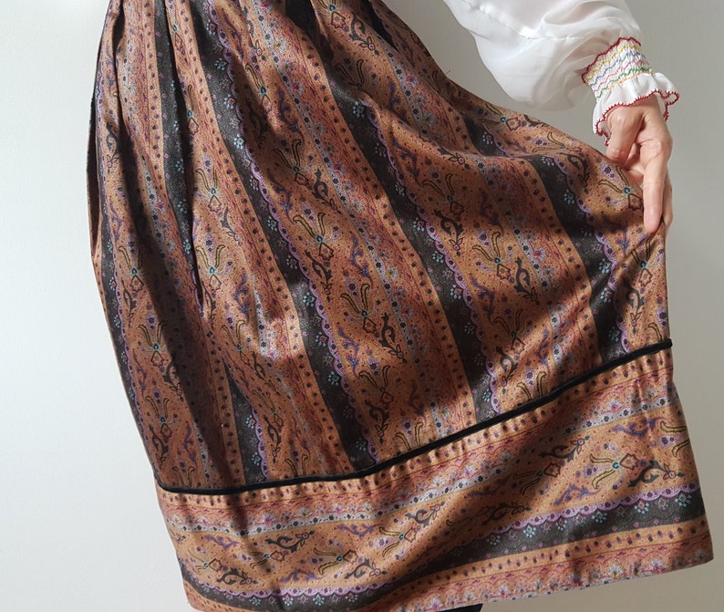 May include: A brown and black patterned skirt with a black velvet trim. The skirt has a vertical striped pattern with a floral design.