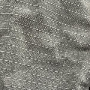 Pu&ograve; includere: Primo piano di un tessuto grigio con un motivo a griglia. Il tessuto ha un aspetto strutturato con una sottile lucentezza. La griglia &egrave; formata da sottili linee bianche che si intersecano per creare piccoli quadrati. L'aspetto generale &egrave; pulito e strutturato.