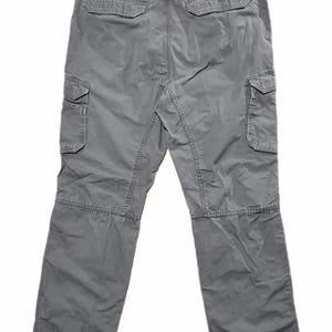 Pu&ograve; includere: Pantaloni cargo grigi con multiple tasche, tra cui due sul retro e due su ogni gamba. I pantaloni hanno una vestibilit&agrave; rilassata e sono realizzati in un tessuto resistente. Il logo Carhartt &egrave; visibile.