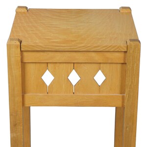 May include: A light wood end table with a single shelf and a decorative openwork design on the top shelf.