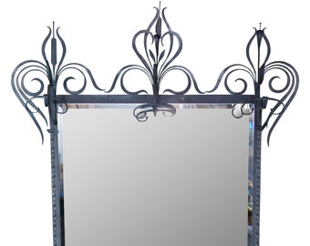 May include: A black wrought iron coat rack with a mirror and a shelf for shoes. The rack has a decorative design with scrolls and leaves.