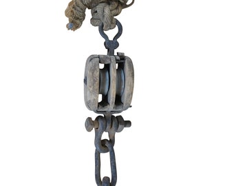 May include: A vintage wooden pulley with two metal wheels and a metal hook. The pulley is attached to a length of rope.