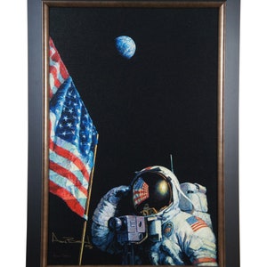 May include: A framed painting of an astronaut saluting the American flag on the moon, with Earth visible in the background. The astronaut is wearing a white spacesuit with the American flag on the helmet and shoulder. The painting is signed by the artist, "Alan Bean".