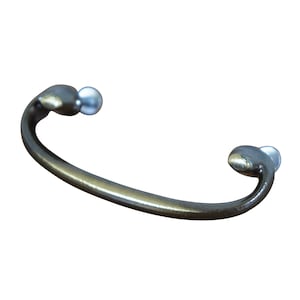 May include: A silver-toned metal cabinet pull with rounded ends. The pull has a curved shape and is designed for use on cabinets or drawers.