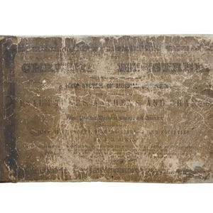 May include: An antique book with a worn, textured cover. The cover is a faded brown with visible text and signs of age, including tears and discoloration. The title and author's name are visible.