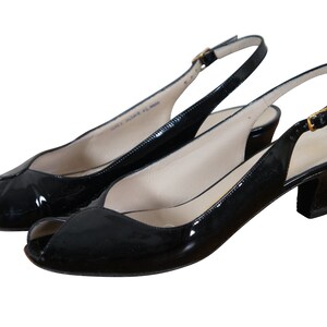 May include: A pair of black patent leather peep-toe slingback heels with a gold buckle.