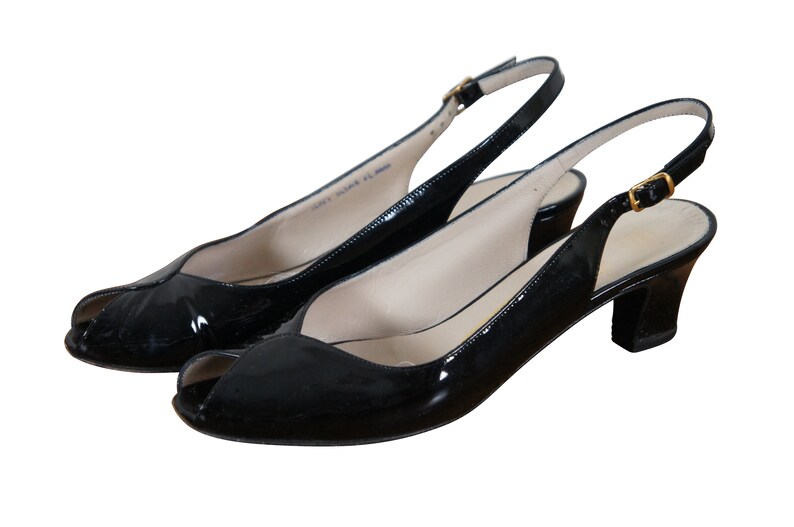 May include: A pair of black patent leather peep-toe slingback heels with a gold buckle.