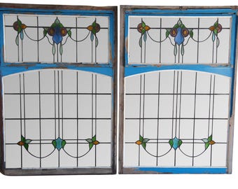 May include: A pair of antique stained glass windows with a blue and white floral design. The windows are framed in wood with a blue paint finish.