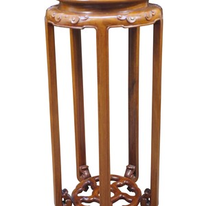 May include: A tall, wooden plant stand with a round top and a decorative, openwork base. The stand is made of a warm-toned wood and features a series of vertical supports. The top has a slightly raised edge. The stand is approximately 30 inches tall.