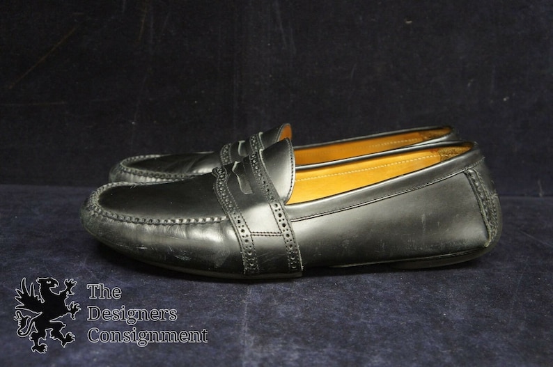 May include: A pair of black leather loafers with a decorative stitch detail. The loafers have a pointed toe and a low heel.