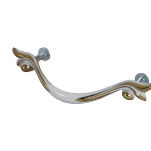 May include: White and gold decorative cabinet pull with a curved design. The pull features a white base with gold accents and decorative flourishes. Includes two silver screws for mounting.