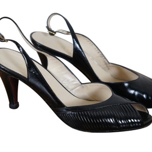 May include: A pair of black leather peep-toe slingback heels with a high stiletto heel.