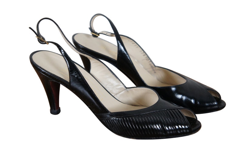 May include: A pair of black leather peep-toe slingback heels with a high stiletto heel.