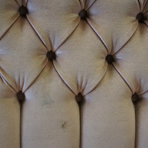 Peut inclure: Gros plan sur un tissu capitonn&eacute; brun clair avec un motif en losange. Le tissu a un l&eacute;ger brillant et est accentu&eacute; par de petits boutons ronds.