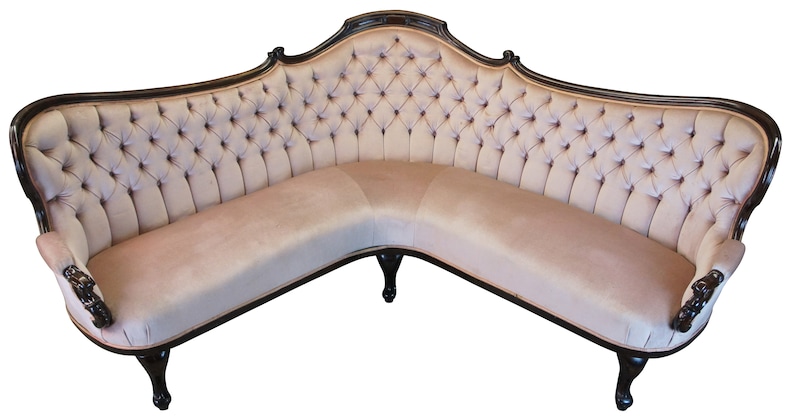 Peut inclure: Un grand canap&eacute; d'angle incurv&eacute; avec un rev&ecirc;tement en tissu beige clair capitonn&eacute; et une structure en bois brun fonc&eacute;. Le canap&eacute; a un design traditionnel et orn&eacute; avec des d&eacute;tails sculpt&eacute;s sur les accoudoirs et les pieds.