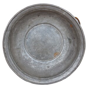 May include: A large, round, silver metal bowl with a slightly raised rim. The bowl has a worn, aged appearance with a dull finish.
