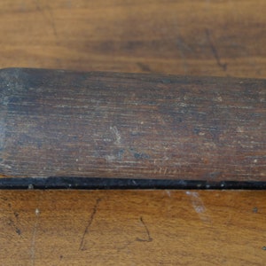 May include: Close-up of a dark brown wooden baseball bat with a smooth, worn surface.