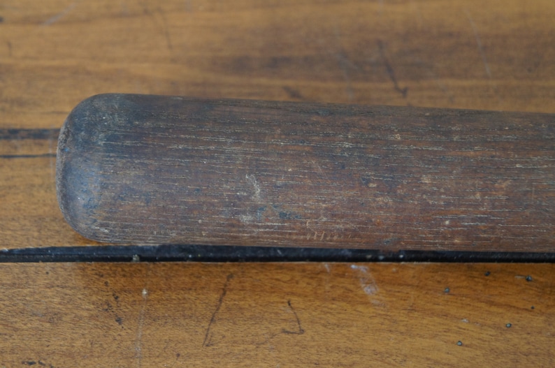 May include: Close-up of a dark brown wooden baseball bat with a smooth, worn surface.