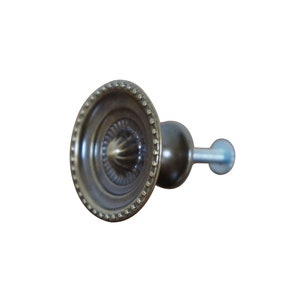 May include: A round, ornate, brass cabinet knob with a decorative design and a screw for attachment.