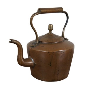 May include: A copper-colored antique kettle with a curved spout and a handle. The kettle has a lid with a small knob and a curved handle. The spout is curved and pointed. The kettle is made of metal and has a vintage look.