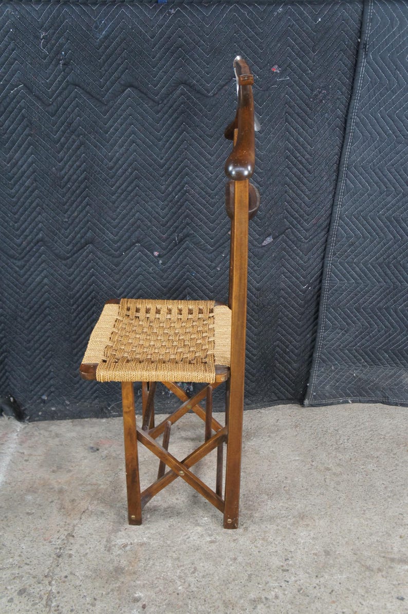 May include: A vintage wooden chair with a woven seat and a tall, curved backrest. The chair has a dark brown finish and a woven seat made of natural fibers. The legs are crossed for stability. The chair is designed for comfort and style.