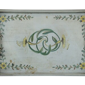 May include: A rectangular wooden serving tray with painted floral designs. The tray has a light gray background with green and yellow floral accents. The tray has two handles on the sides.