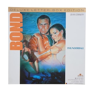 May include: A vintage "Thunderball" laserdisc box set featuring Sean Connery. The cover art showcases a man and woman in a water scene, with the word "BOND" in orange. The box is labeled "DELUXE LETTER-BOX EDITION".