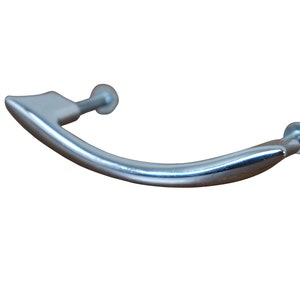 May include: A silver-toned, curved cabinet pull with a pointed end. The pull has two screw holes.
