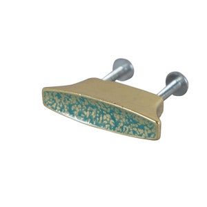 May include: A gold-colored cabinet knob with a teal-colored, speckled design. The knob has two silver screws.