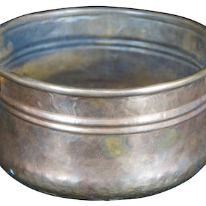 May include: A copper-colored metal bowl with two handles. The bowl has a rounded shape with a wide opening and a hammered texture. The handles are a lighter color, possibly brass or bronze.