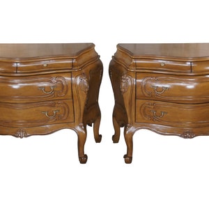 May include: Two matching wooden nightstands with ornate carvings and three drawers each. The nightstands have a rich brown finish and are made of solid wood.