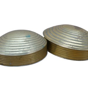 May include: Two decorative clam shell-shaped boxes. The lids are silver-colored with concentric ridges, and the bases are gold-colored. The boxes are likely used for storing small items or as decorative pieces.