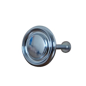 May include: A silver-toned curtain rod finial with a round, decorative top and a small, round knob on the end.