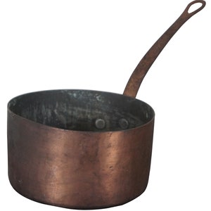 May include: A vintage copper saucepan with a long handle. The saucepan has a worn, aged patina and is perfect for cooking on a stovetop.