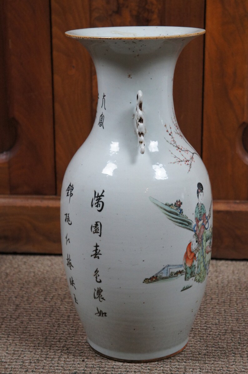 Op de afbeelding: Een witte porseleinen vaas met twee handvatten en een bloemenmotief. De vaas heeft Chinese karakters aan de zijkant, waaronder "Qing-dynastie" en "Gemaakt in China".