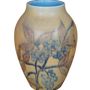 May include: A yellow ceramic vase with a blue glaze and a floral design. The vase has a round body and a narrow neck.