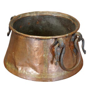 May include: A large copper pot with two iron handles. The pot has a rounded bottom and a wide opening. The pot is old and has a patina of age.