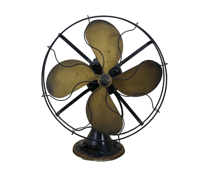 Puede incluir: Un ventilador el&eacute;ctrico antiguo con cuatro aspas de color lat&oacute;n y un marco de metal negro. El ventilador tiene una jaula circular y una base negra. Las aspas son curvas y tienen p&aacute;tina. Un art&iacute;culo de decoraci&oacute;n vintage.