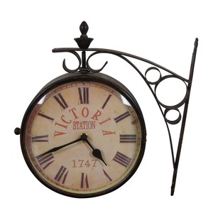 May include: A vintage-style metal clock with a black face and Roman numeral markings. The clock face reads "Victoria Station 1747". The clock is attached to a black metal bracket.