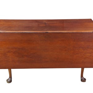 May include: A rectangular, wooden drop-leaf table with a rich, brown finish. The table features a hinged top that can be folded down. The legs are curved and end in a ball-and-claw foot design. A classic piece of furniture.