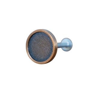 May include: A round, copper-colored curtain rod finial with a textured, dark gray surface. The finial has a silver-colored stem.
