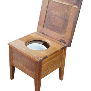 May include: An antique wooden commode with a hinged lid. The commode has a square seat with a circular opening and a white ceramic bowl. The wood has a warm, reddish-brown tone and is supported by four legs.