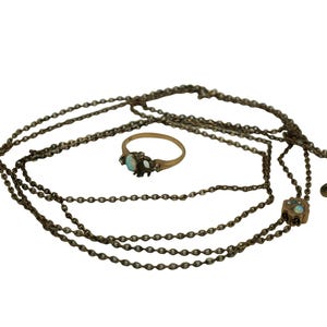 May include: A gold chain necklace with three strands and a small ring with a blue stone and gold accents.