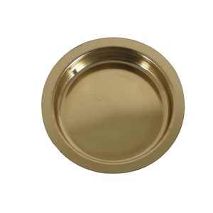May include: A round, gold-colored metal plate with a raised edge. The plate is smooth and shiny.