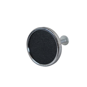May include: A round, black knob with a silver trim and a small, white plastic post. The knob is designed for use on furniture or cabinets.