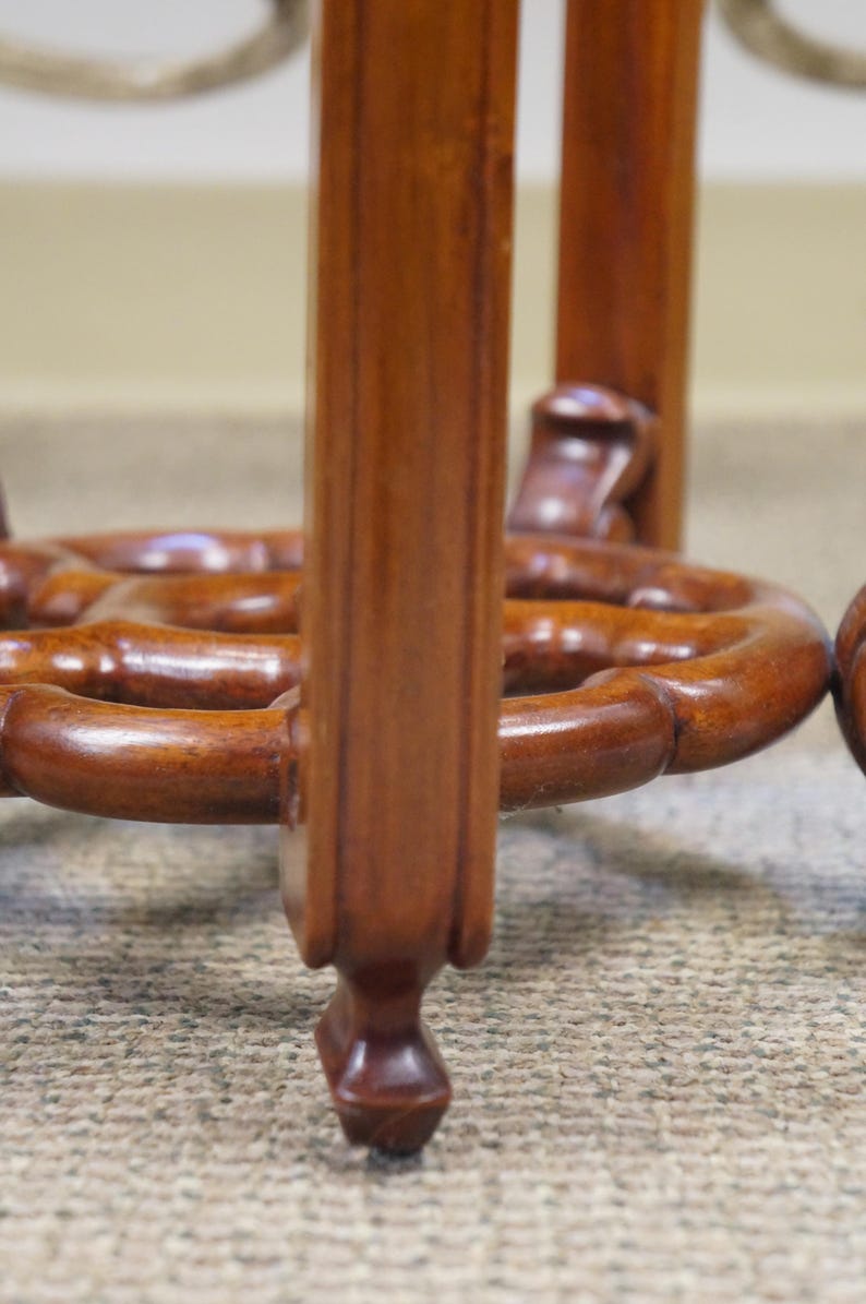 May include: Close-up of a wooden table base with a rich, brown finish. The base features intricately carved details, including a circular design and rounded legs. The wood grain is visible, adding to the table's classic aesthetic.