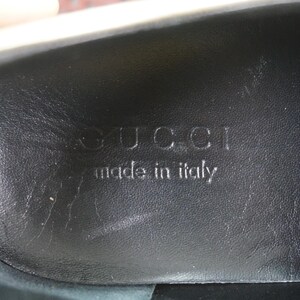 May include: Close-up of the interior sole of a black shoe. The embossed text reads "GUCCI made in italy". The leather sole has a textured appearance.