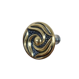 May include: Gold and black decorative knob with a swirling design. The knob has a small silver post on the side.